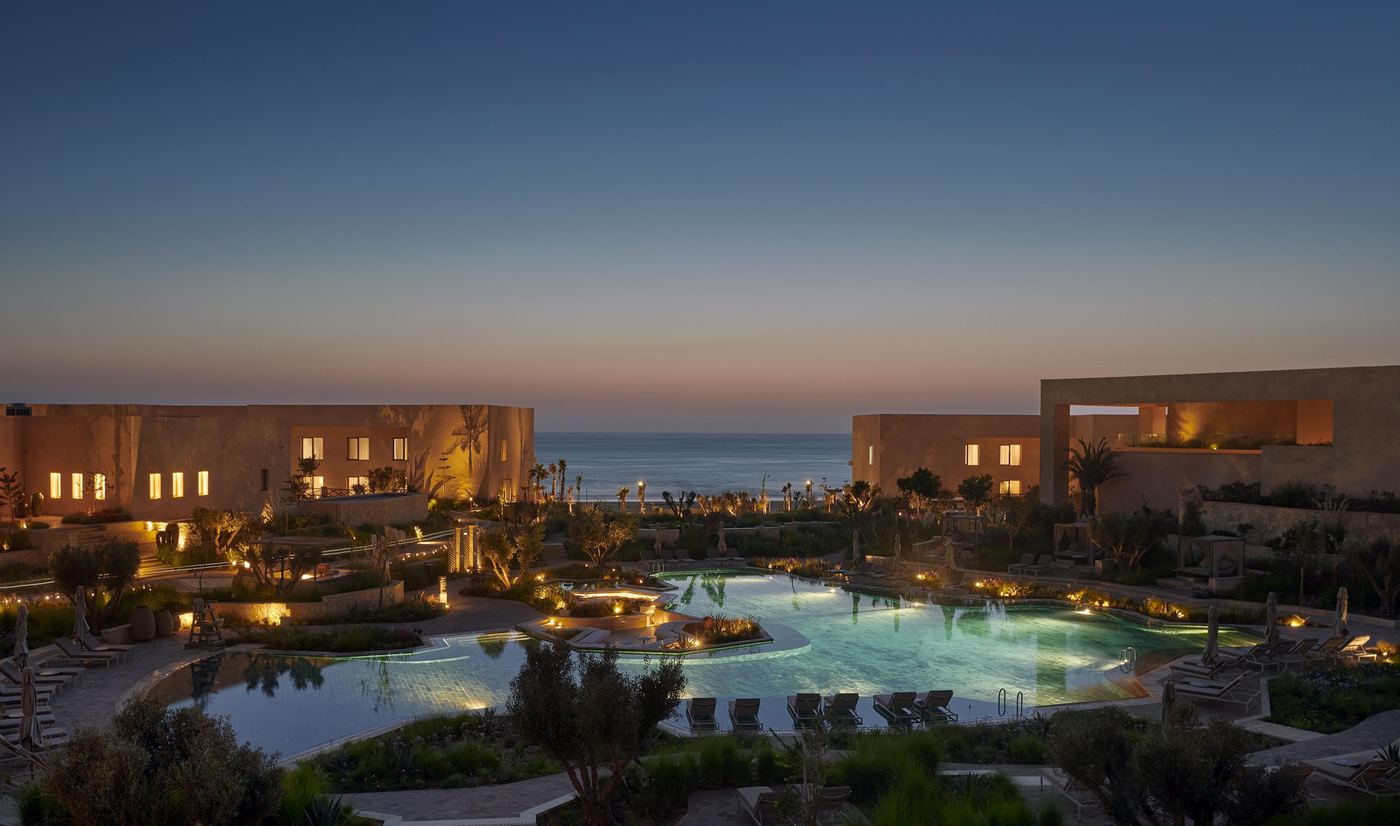 Piscine et jardins d'un hôtel partenaire à Taghazout Bay, à l'heure dorée du crépuscule