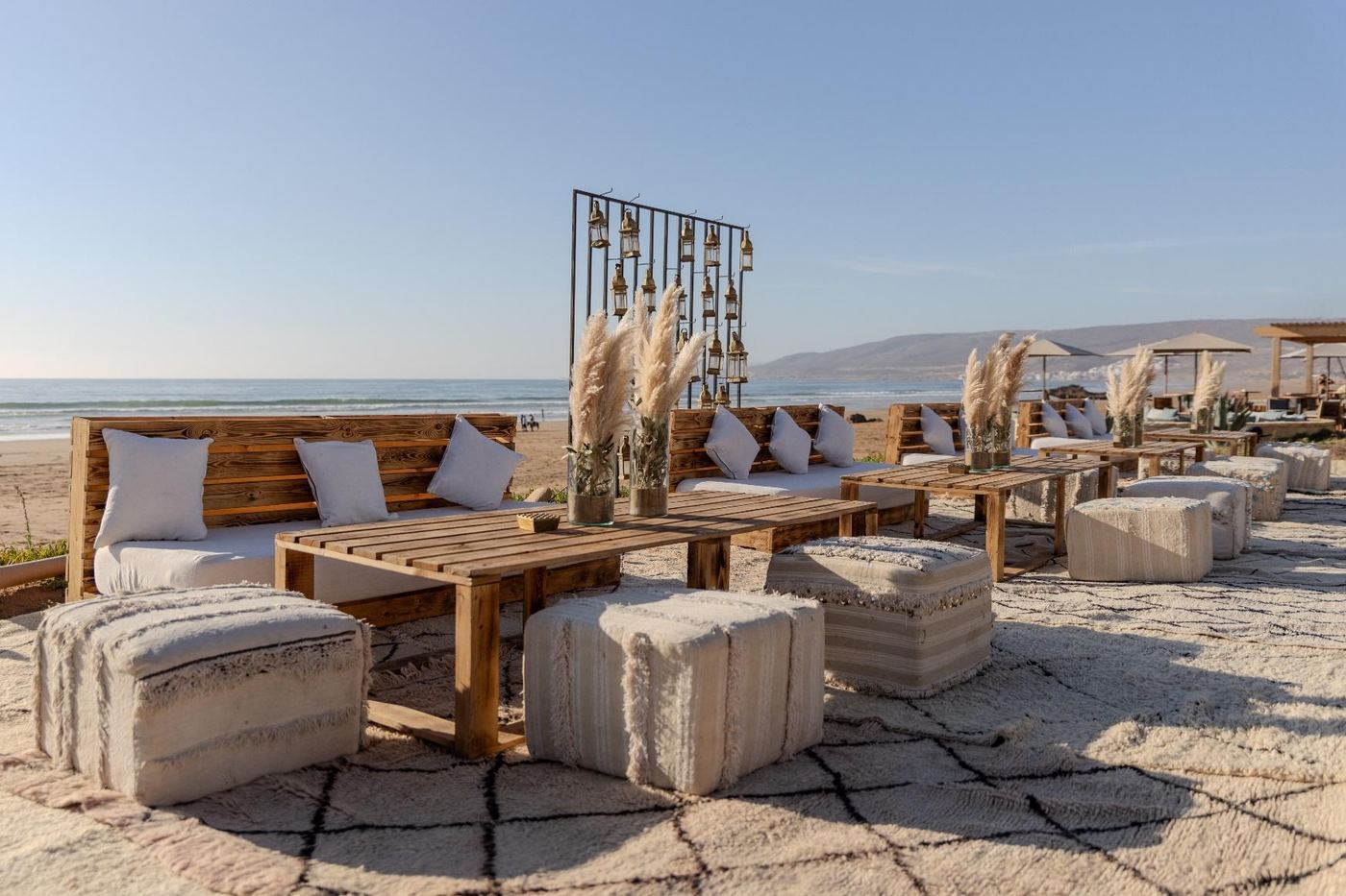Salon en plein air face à la plage, coussins et banquettes en bois